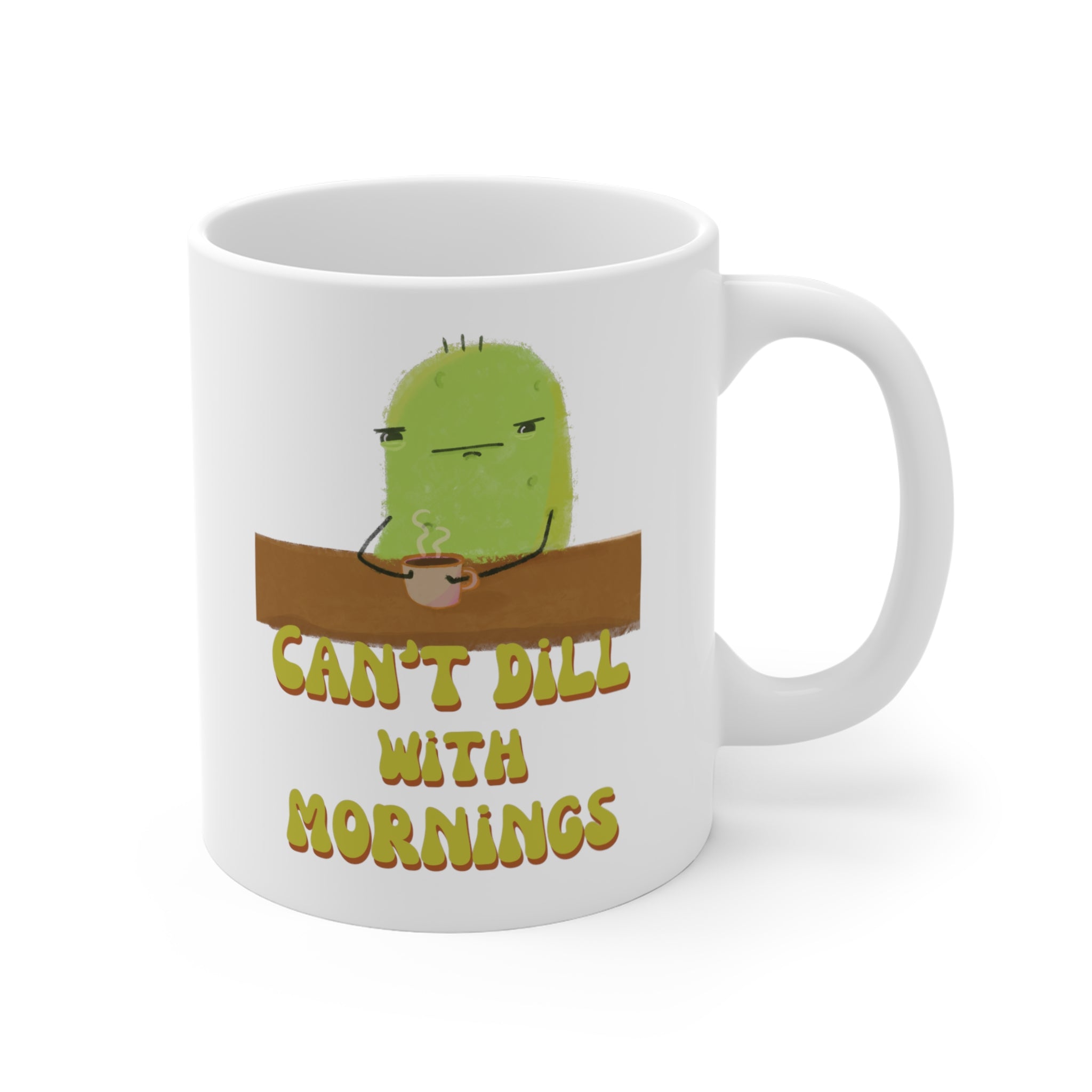 a pickle mug with a cute illustration of a pickle character drinking coffee over a punny quote that says "can't dill with mornings" is displayed over a white background