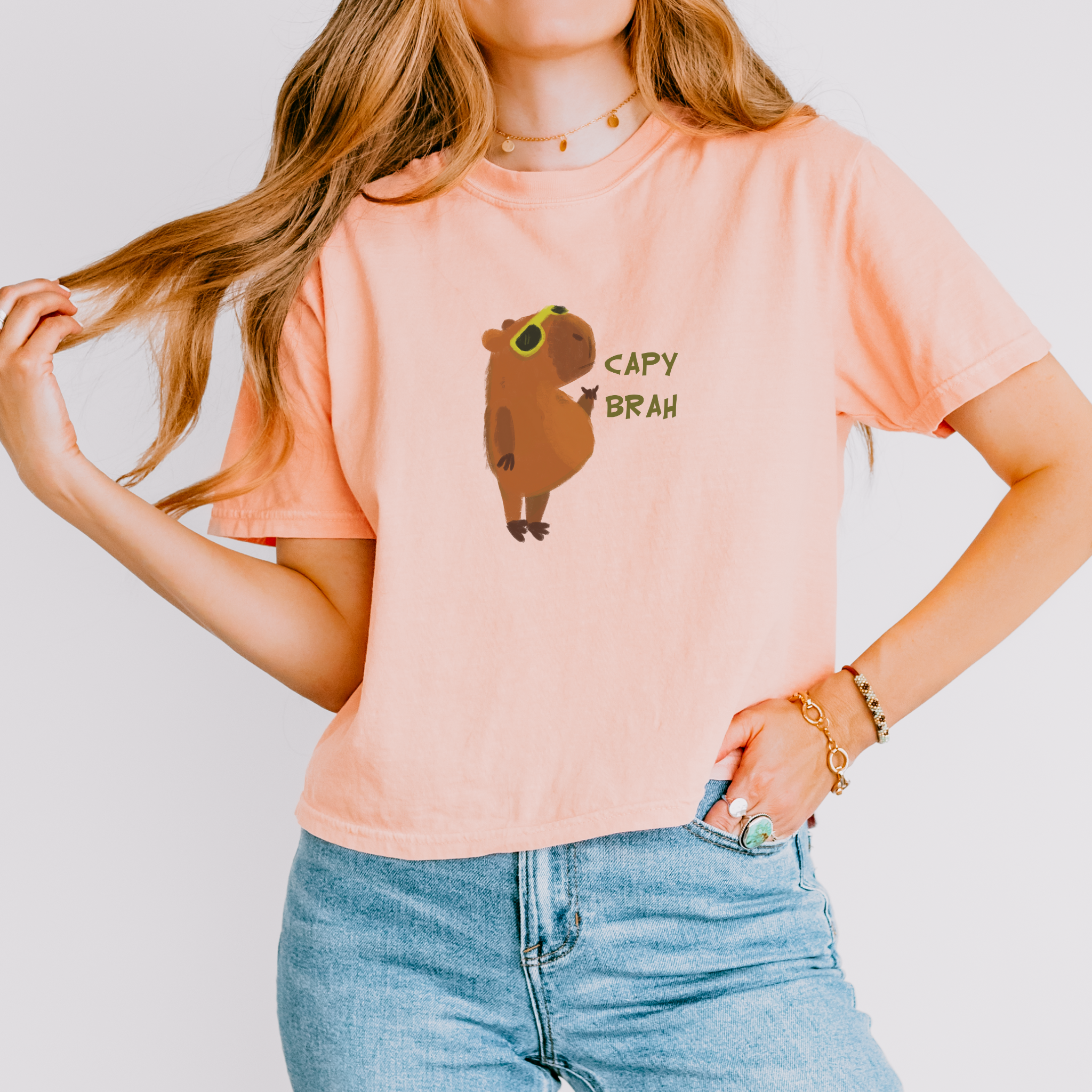 A pink boxy fit t-shirt featuring a graphic of a capybara with the text 'CAPY BRAH' on the front.