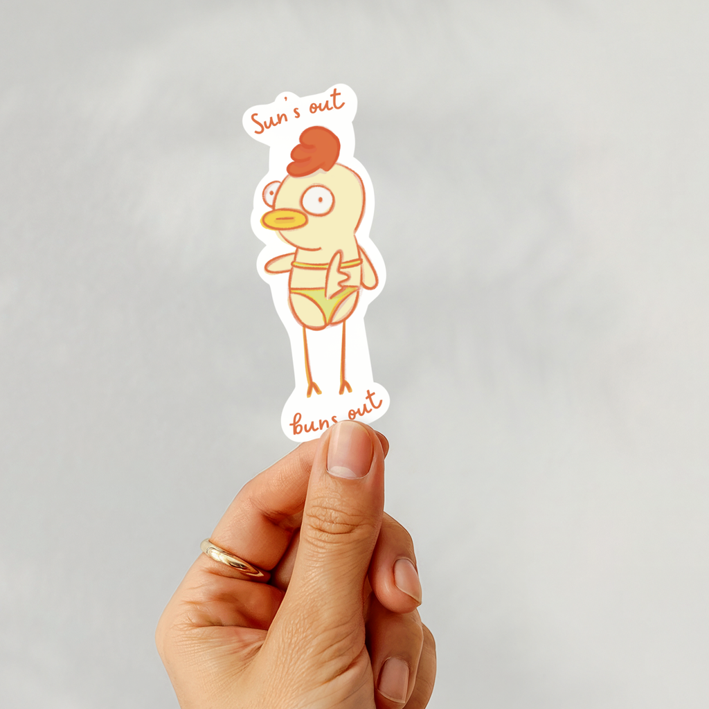 Hand holding a sticker with a cartoon chicken wearing a swimsuit on a gray background